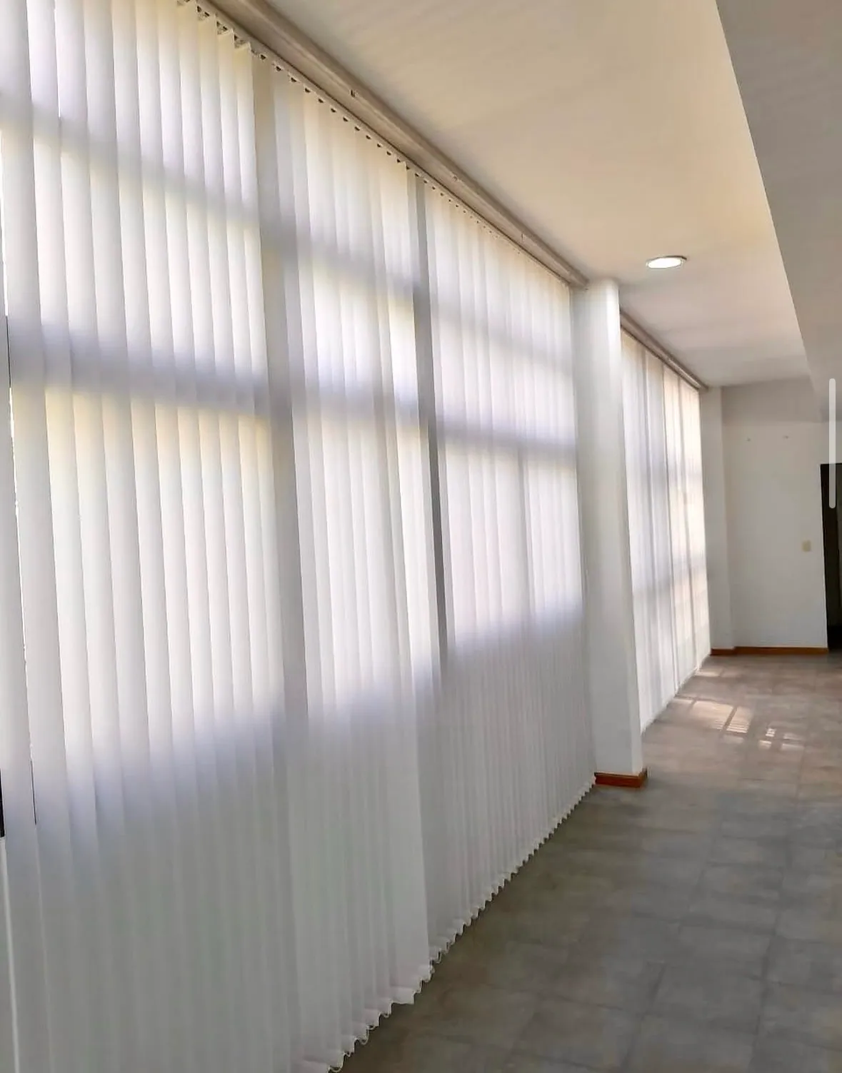 Cortina de bandas verticales con la luz del sol proyectando sombras
